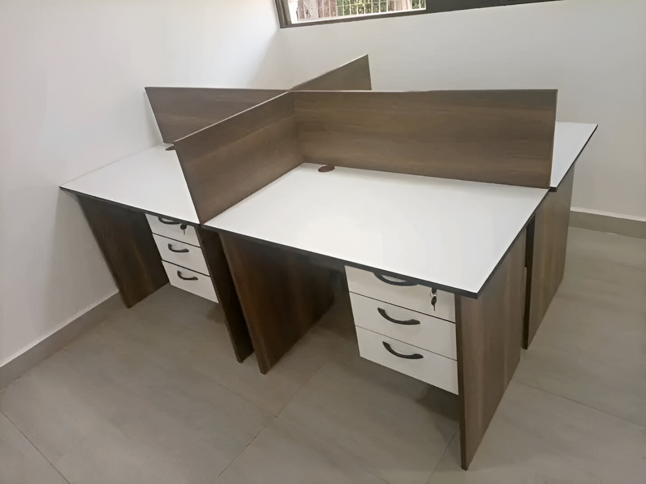 Modern 4-way office workstation with white desktops, privacy panels, and lockable storage drawers for corporate and co-working spaces.