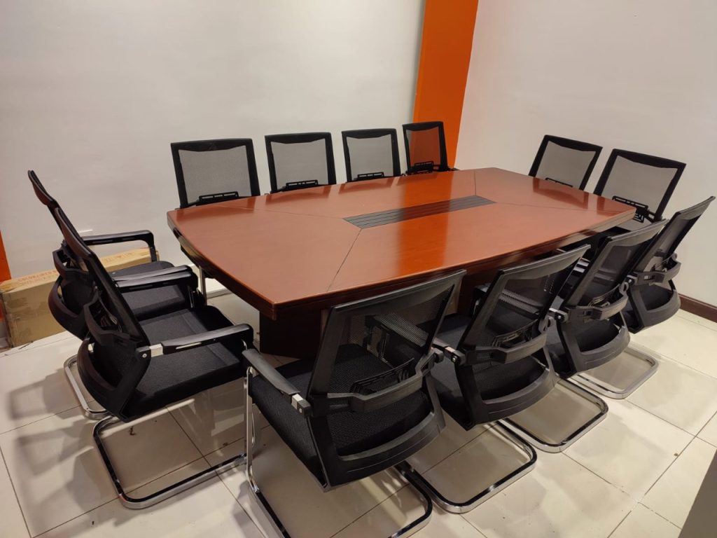 Executive 2400mm boardroom table with mahogany finish and integrated cable management surrounded by black executive chairs in corporate conference room